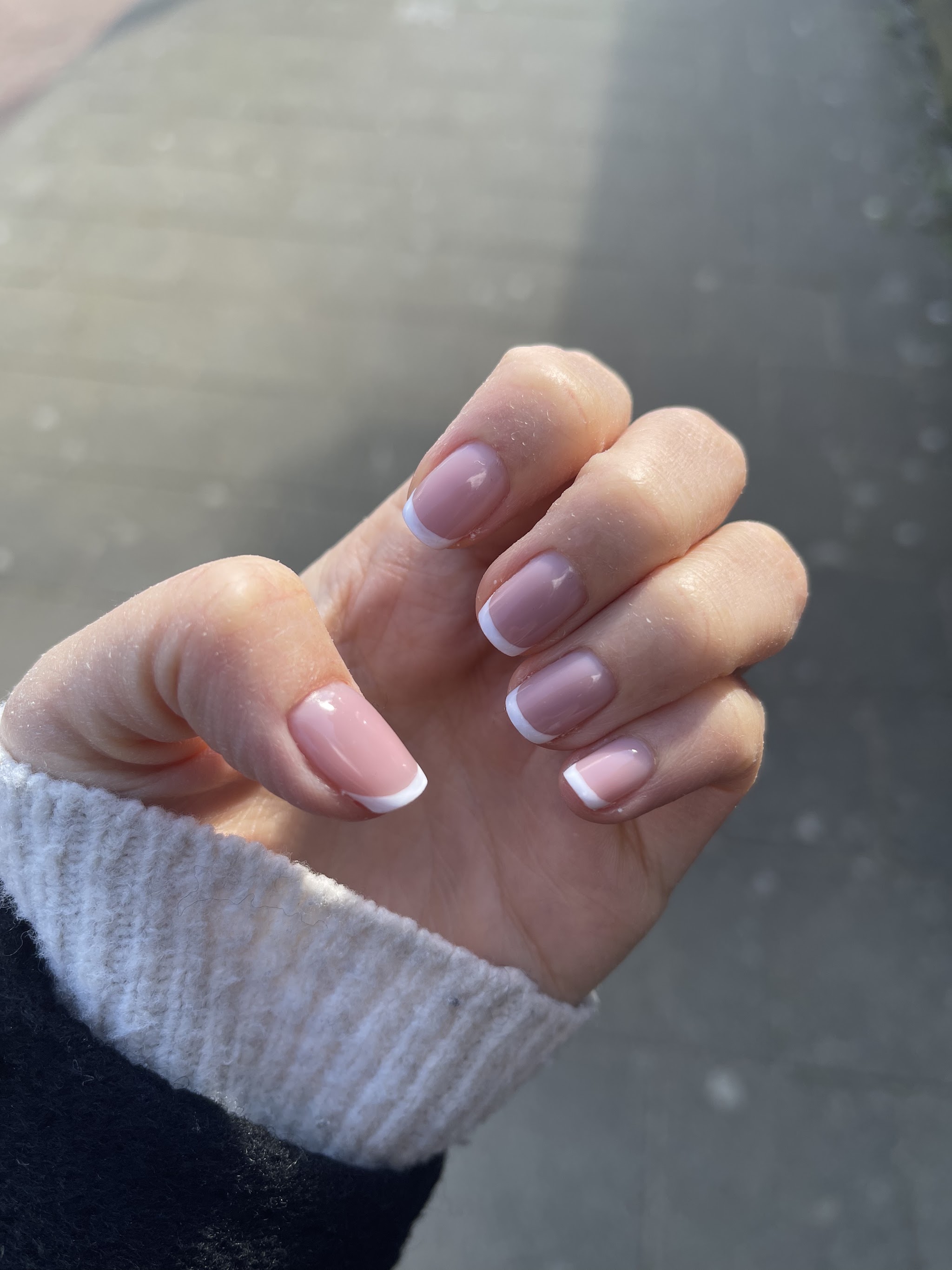 French tips op korte nagels, hand boven een witte trui