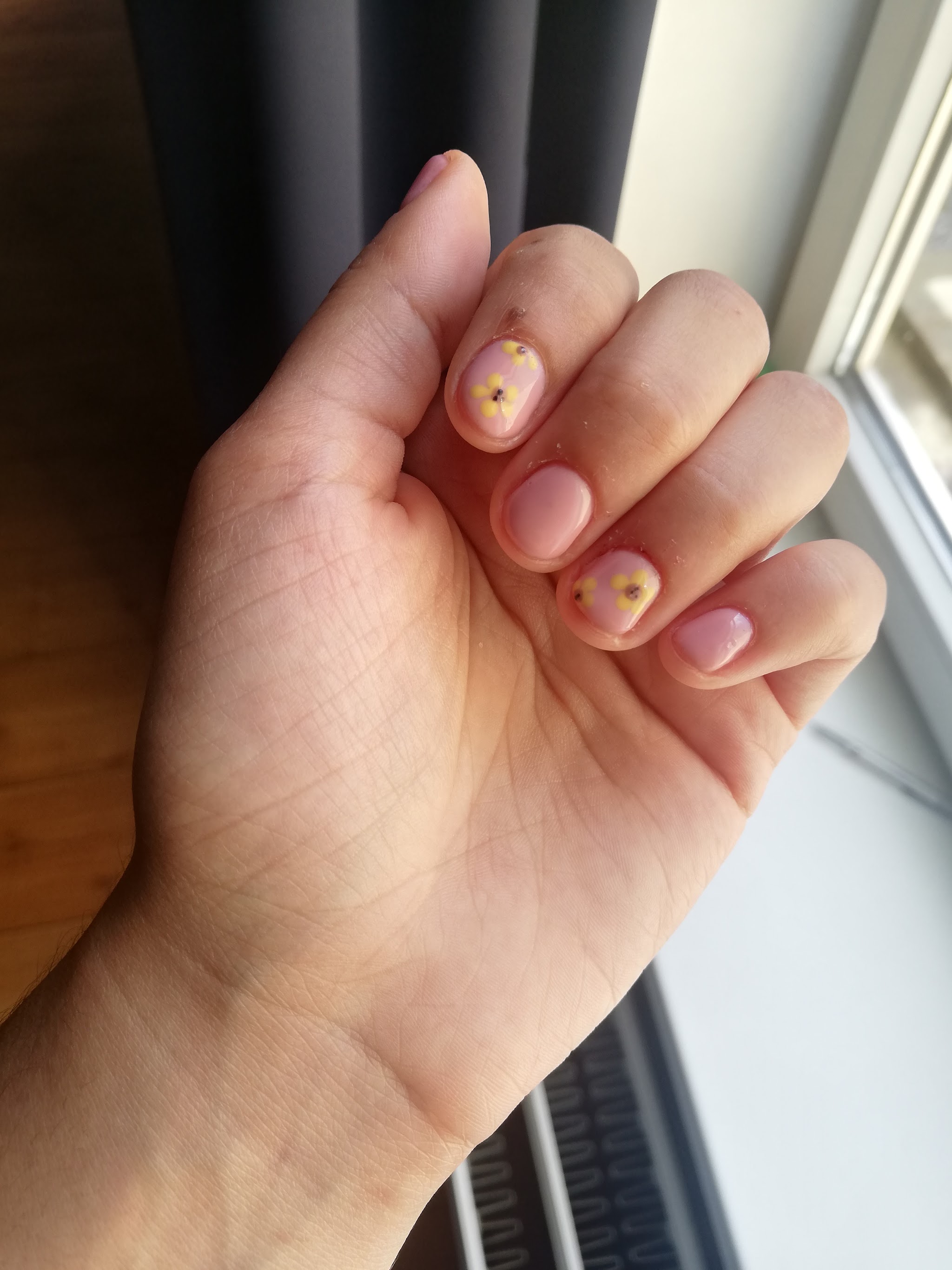Naturel nagels met kleine bloemetjes als nail art, bij het raam